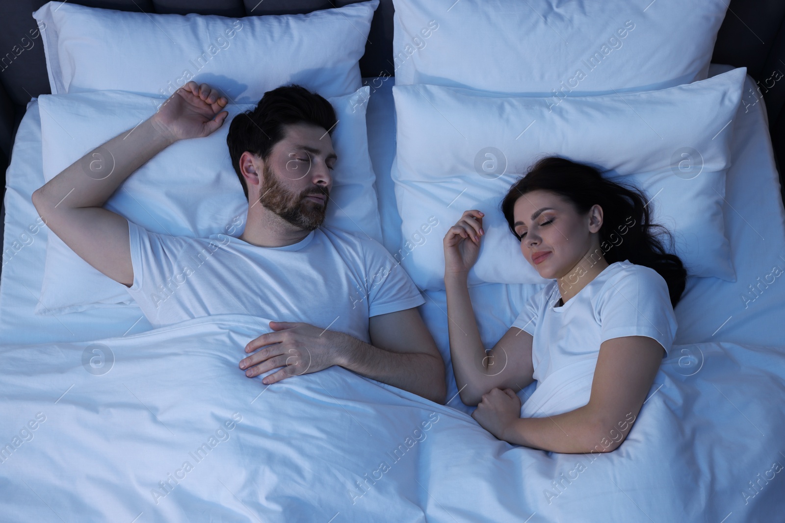 Photo of Lovely couple sleeping together in bed at night, top view