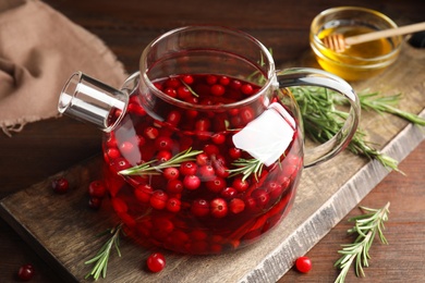 Photo of Tasty hot cranberry tea and fresh ingredients on wooden table