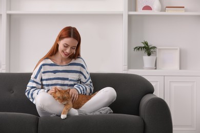 Happy woman with her cute cat on sofa at home, space for text