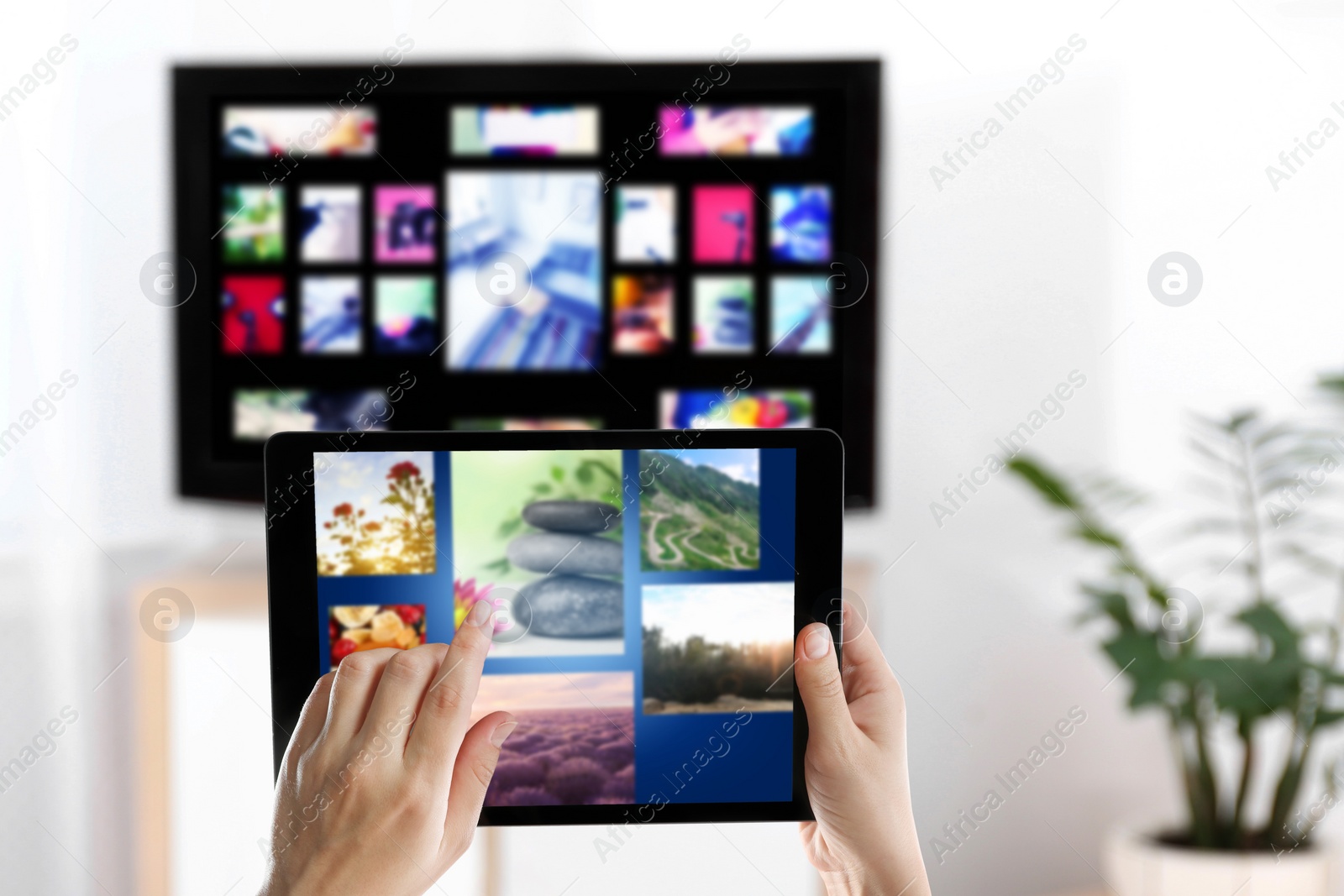 Image of Streaming video services. Woman using tablet to change channels on TV, closeup