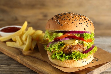 Photo of Burger with delicious patty, french fries and sauce on wooden table, closeup