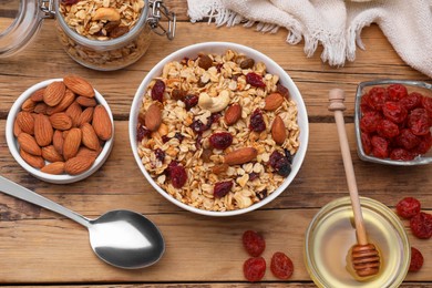 Photo of Tasty granola served with nuts and dry fruits on wooden table, flat lay