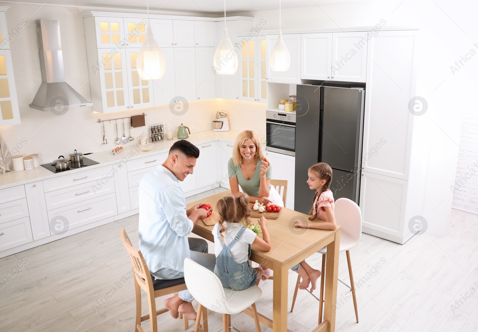 Photo of Happy family cooking together at table in modern kitchen