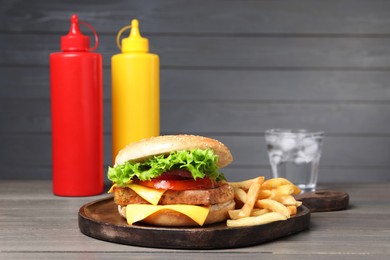 Photo of Delicious tofu burger served with french fries on grey wooden table
