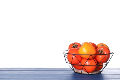 Photo of Delicious ripe juicy persimmons in basket on wooden table against white background