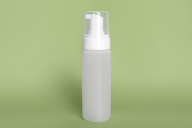 Bottle of face cleansing product on olive background. Space for text