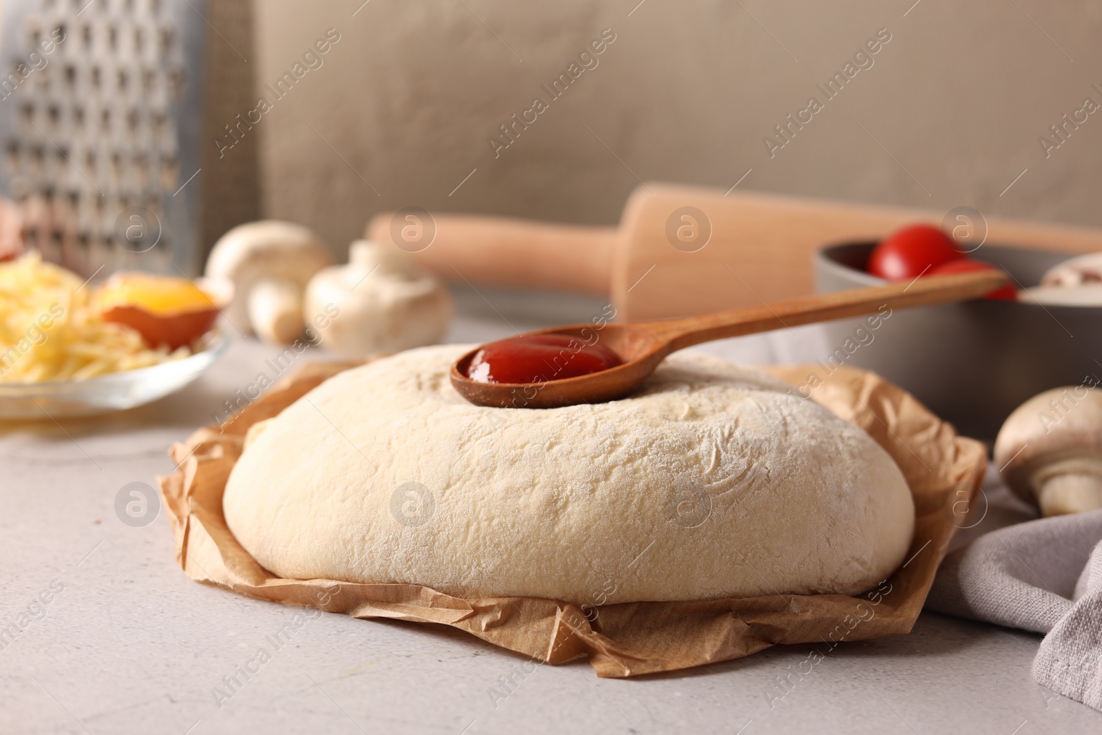 Photo of Pizza dough and products on gray textured table, closeup