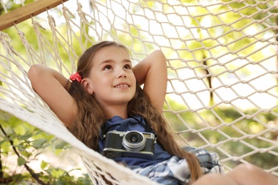 Little girl with camera in hammock outdoors. Summer camp