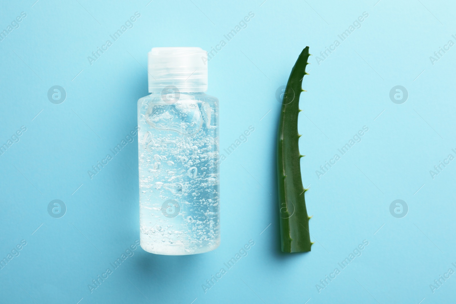 Photo of Bottle of cosmetic gel and aloe on light blue background, flat lay