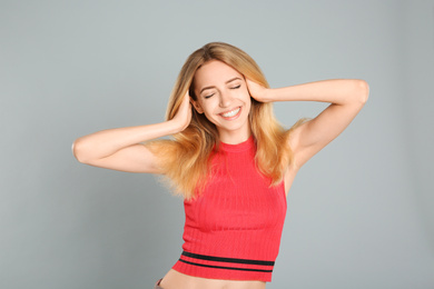 Photo of Portrait of beautiful young woman with blonde hair on grey background