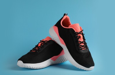 Pair of comfortable sports shoes on light blue background