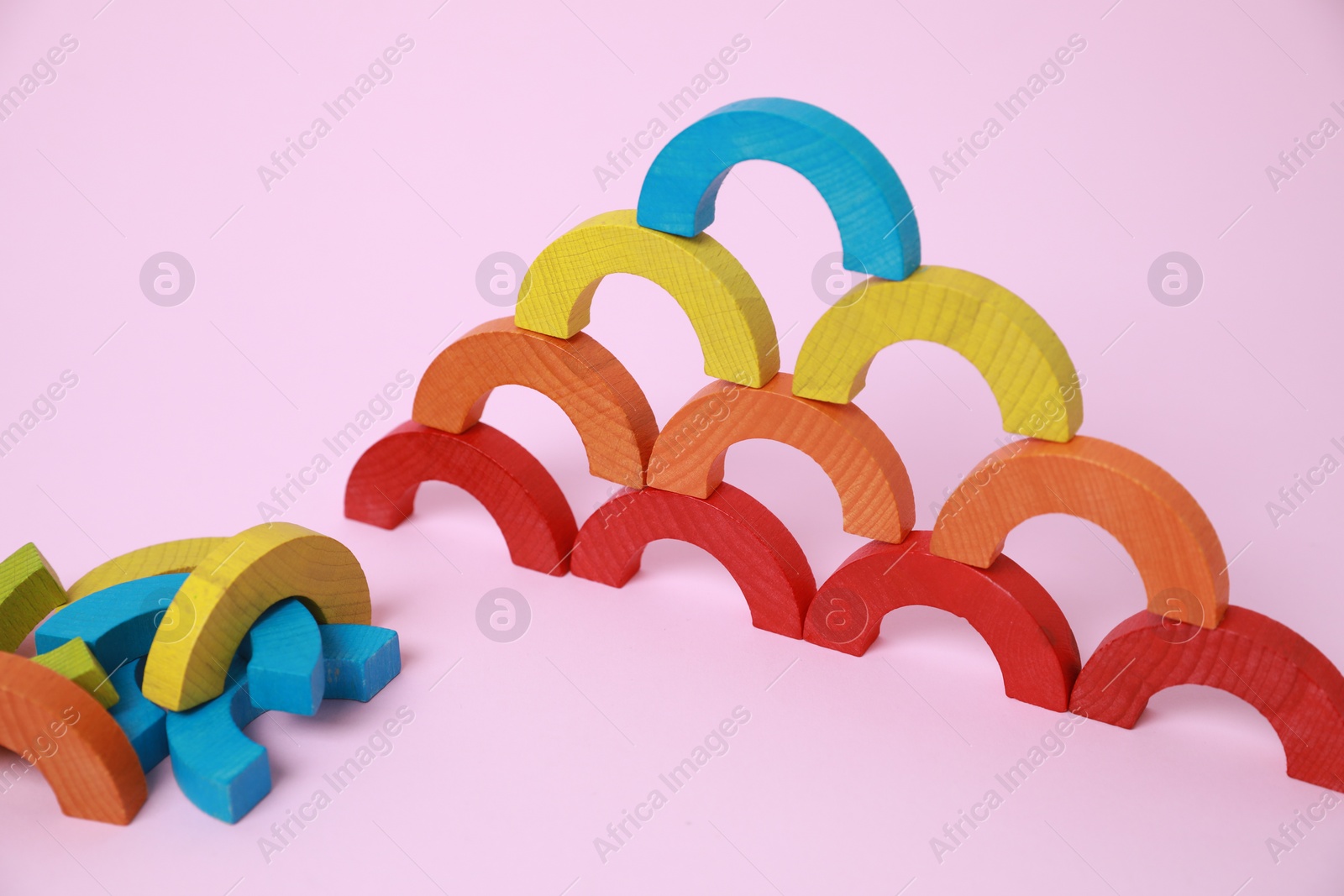 Photo of Colorful wooden pieces of playing set on pink background. Educational toy for motor skills development