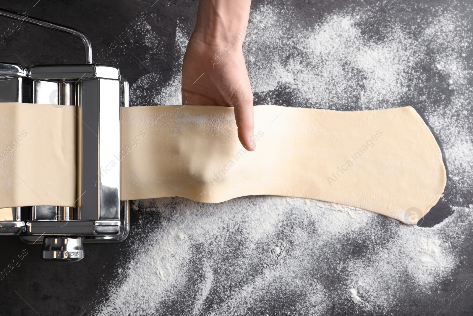 Photo of Young man preparing noodles on pasta maker at table, top view