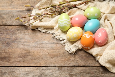 Photo of Flat lay composition with colorful painted Easter eggs on wooden table, space for text