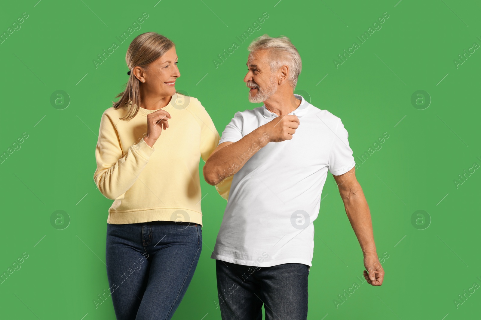 Photo of Senior couple dancing together on green background