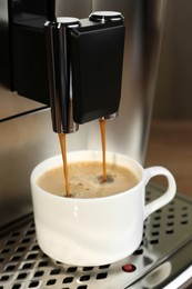 Photo of Modern espresso machine pouring coffee into cup on wooden background, closeup