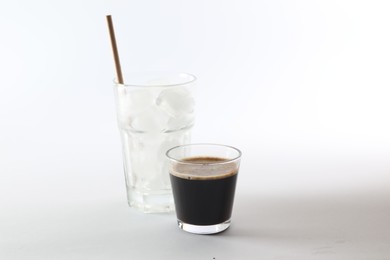 Coffee and ice cubes in different glasses on white background