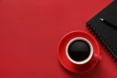Cup with aromatic coffee, notepad and pencil on red background, flat lay. Space for text