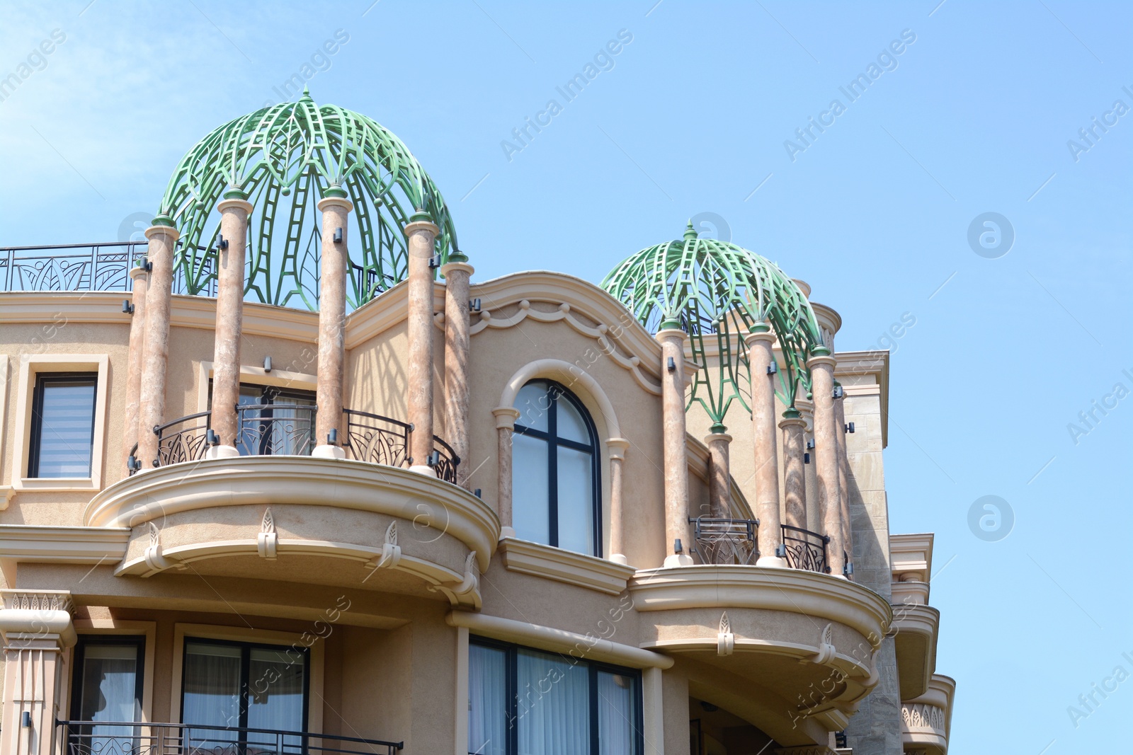 Photo of Exterior of beautiful building with decorated balconies against blue sky
