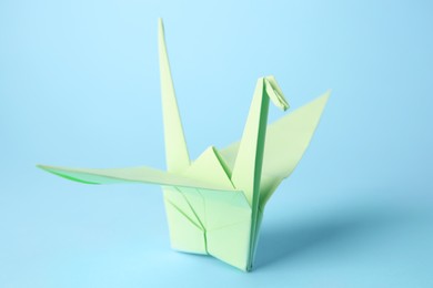 Origami art. Handmade paper crane on light blue background, closeup