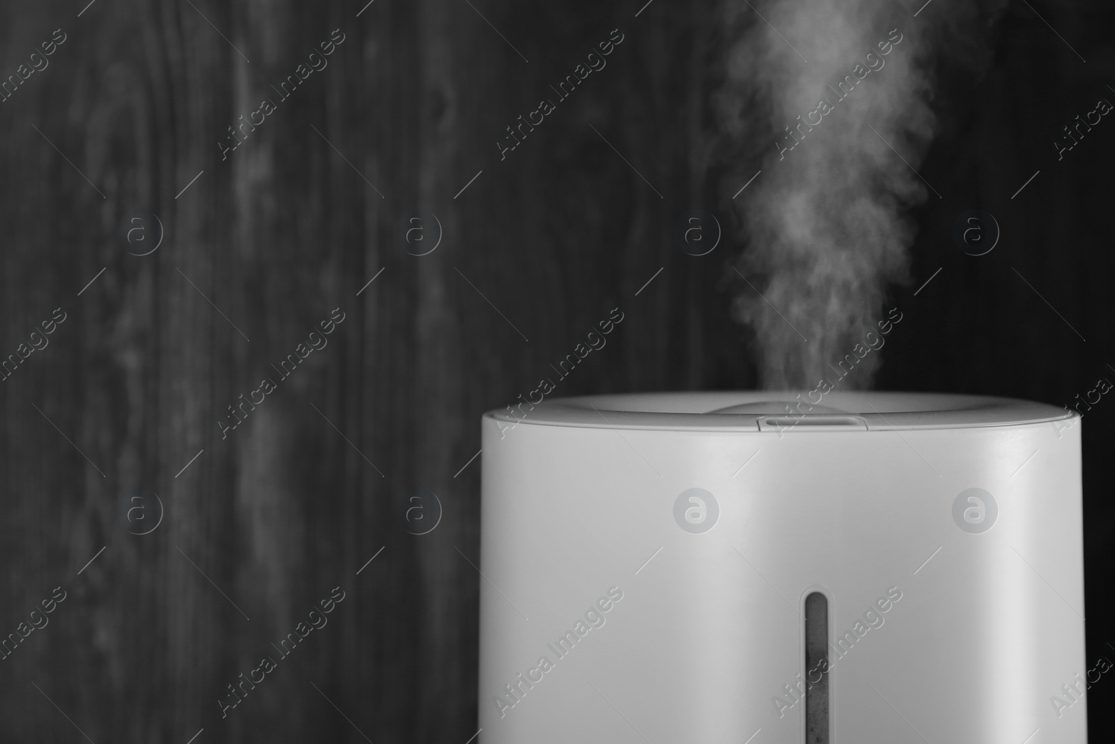 Photo of Modern air humidifier on wooden background, closeup. Space for text