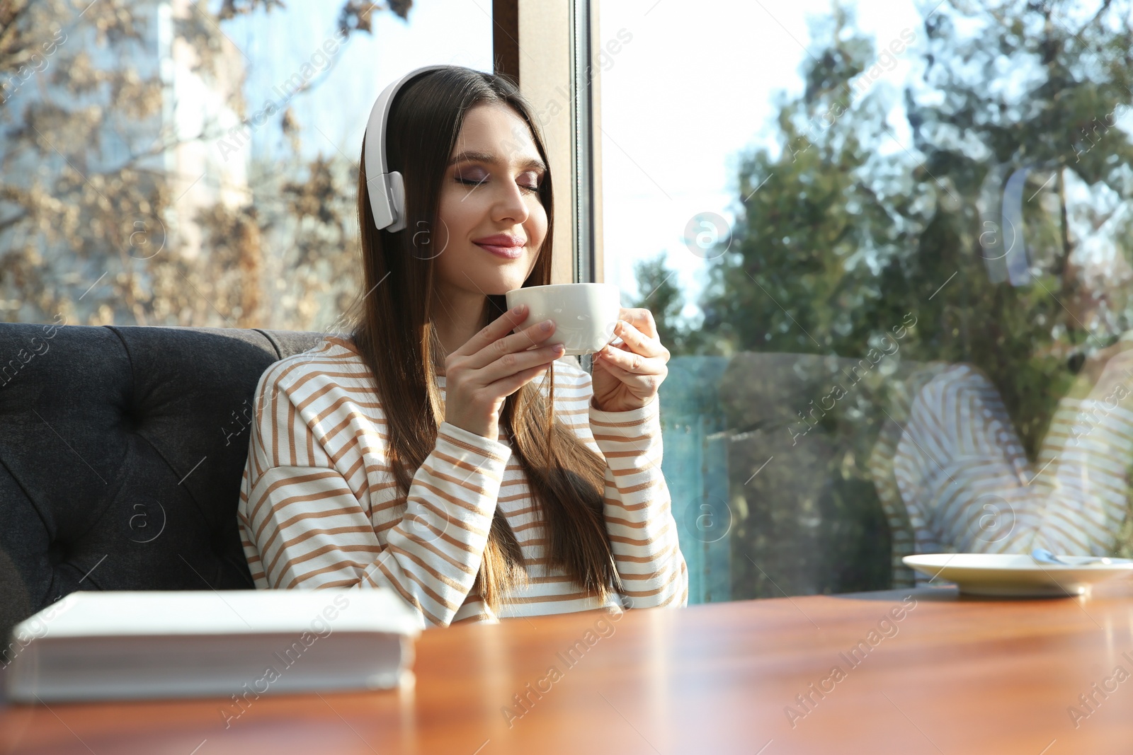 Photo of Woman listening to audiobook at table in cafe