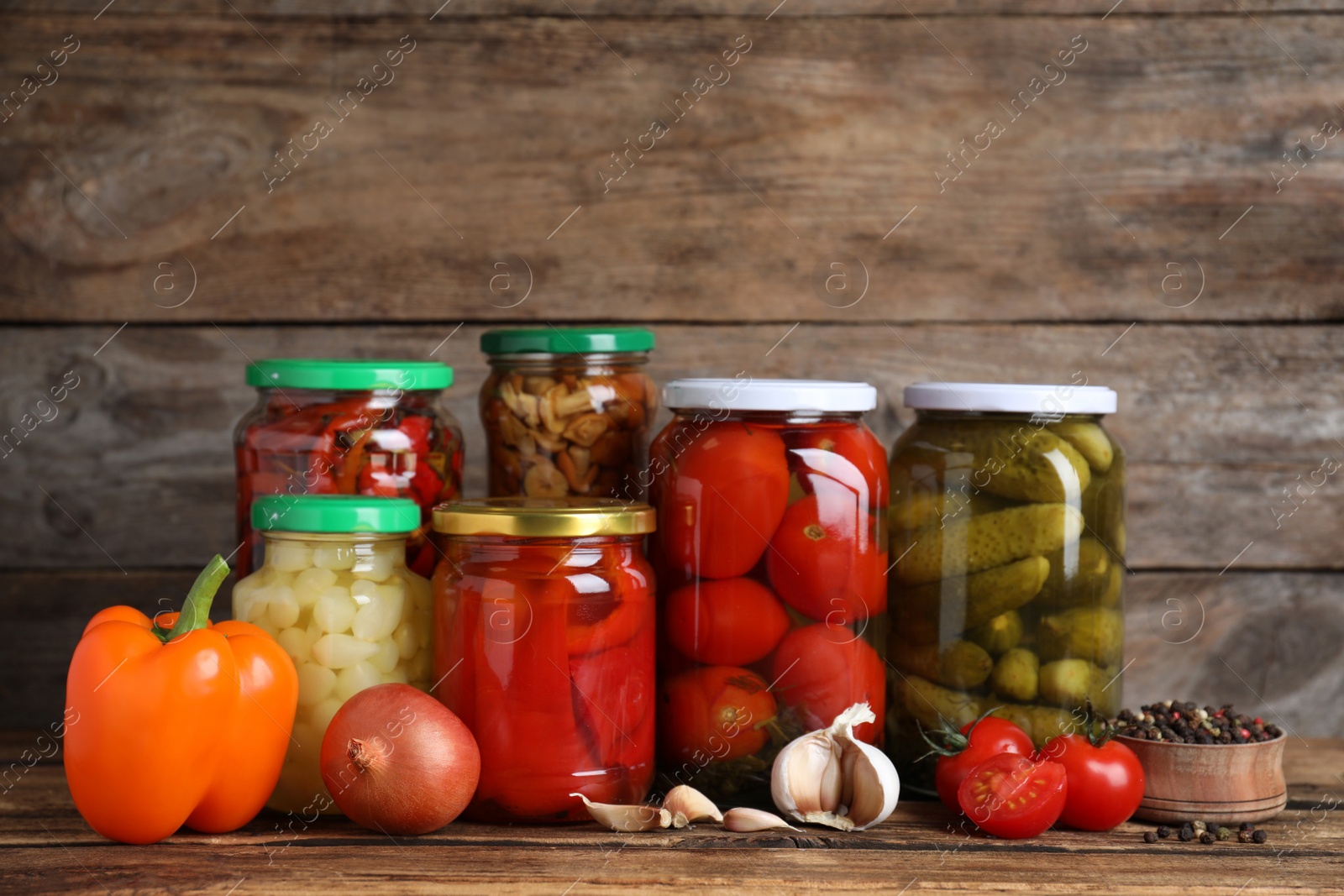 Photo of Glass jars with different pickled vegetables on wooden table