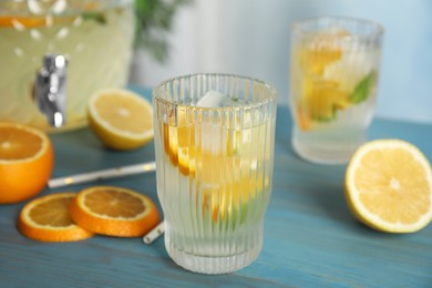 Photo of Delicious refreshing lemonade with orange slices on light blue wooden table