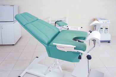 Photo of Examination room with gynecological chair and medical equipment in clinic