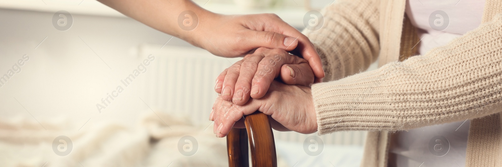 Image of Caregiver and elderly woman with walking cane at home, closeup. Banner design