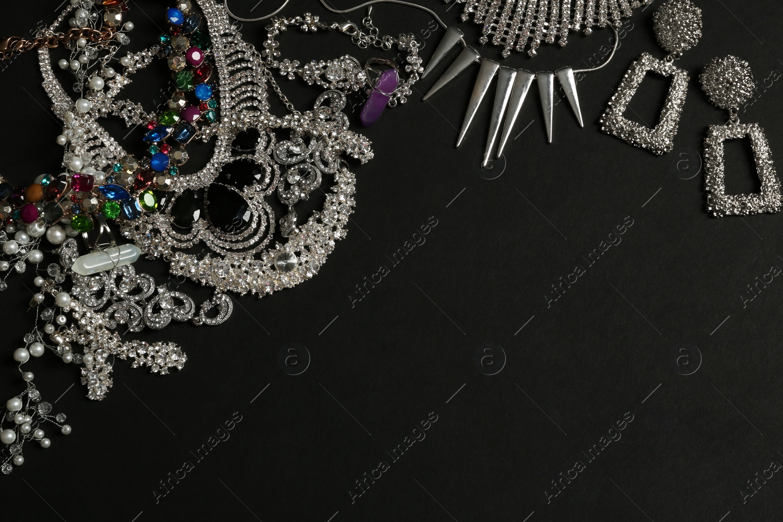 Photo of Different elegant jewelry on black background, top view. Space for text