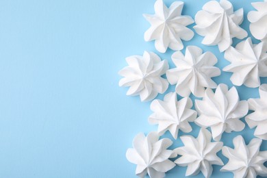 Photo of Tasty meringue cookies on light blue background, flat lay. Space for text