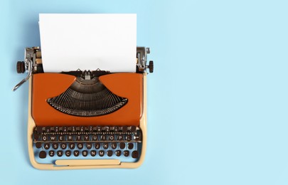 Vintage typewriter on light blue background, top view. Space for text