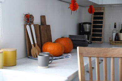 Photo of Fresh ripe pumpkins on countertop in kitchen decorated for Halloween