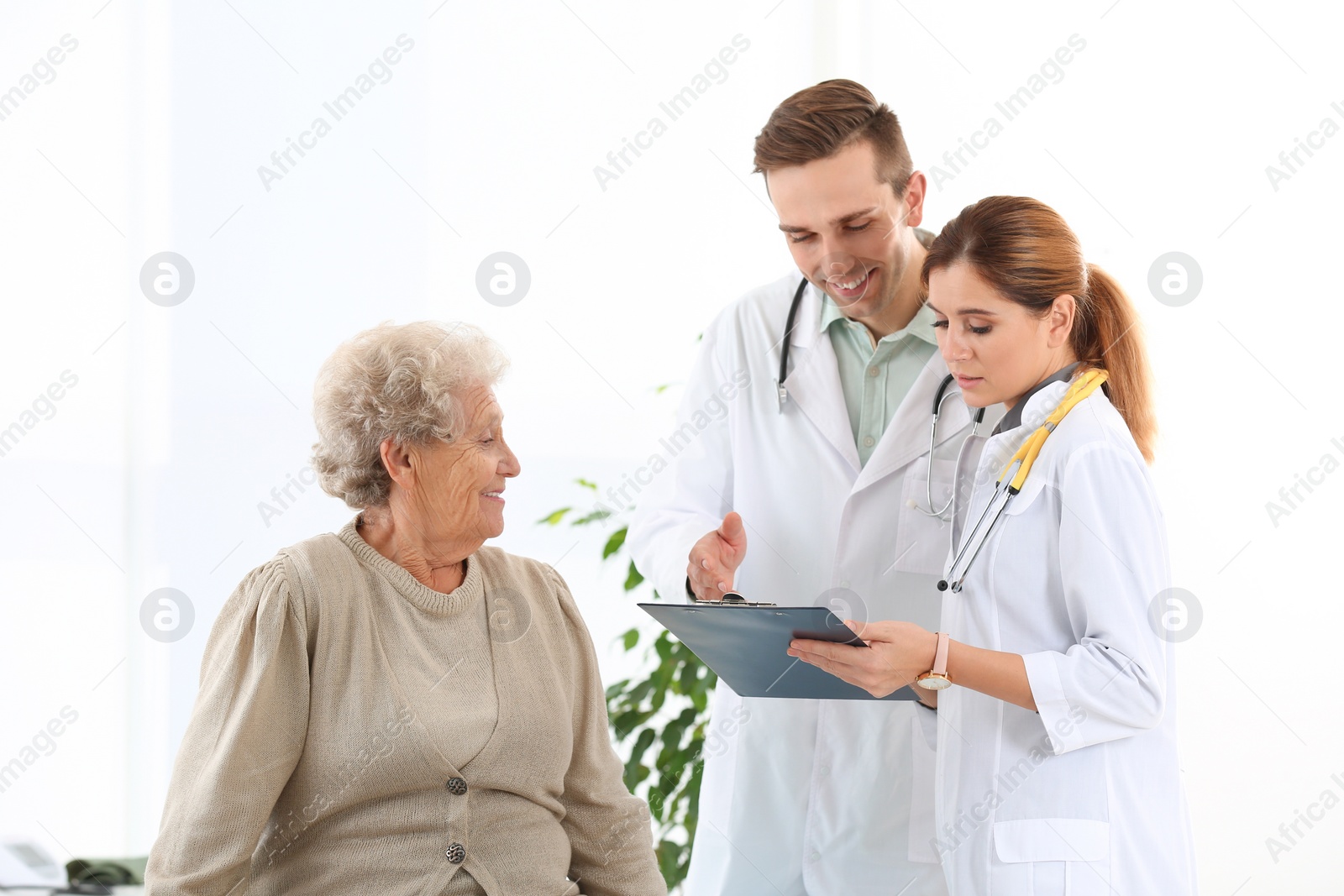 Photo of Doctor and medical assistant working with elderly patient in hospital