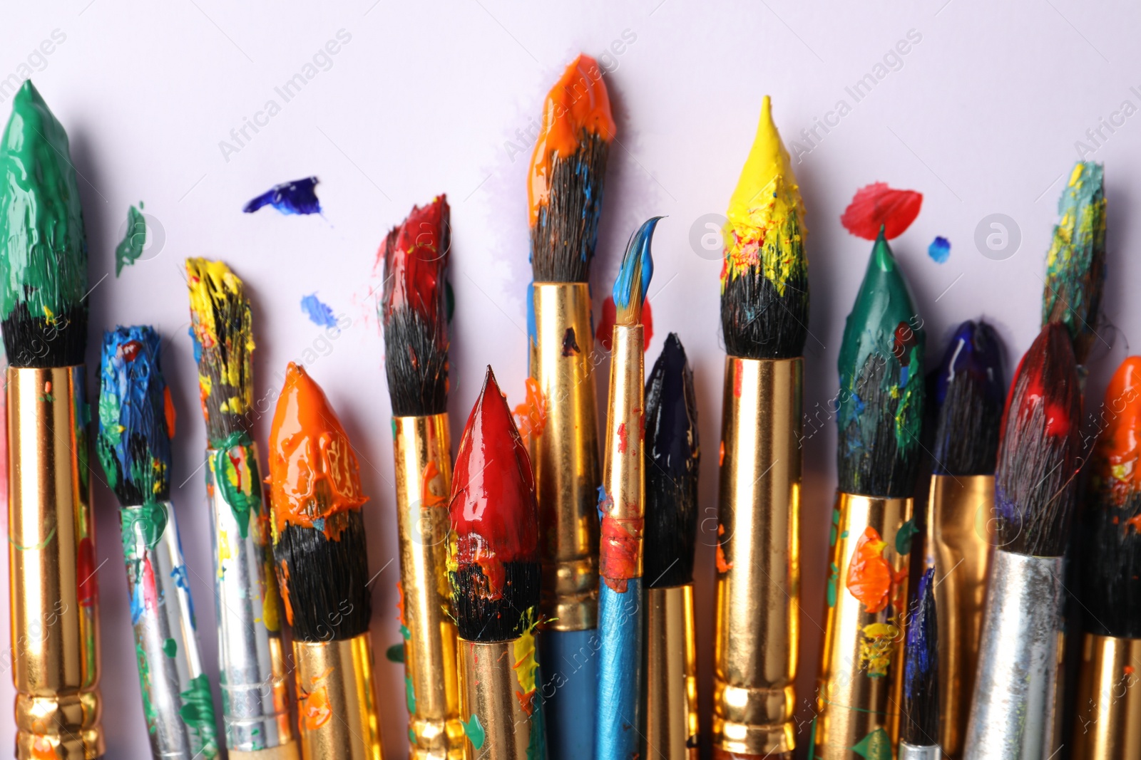 Photo of Brushes with colorful paints on white background, flat lay