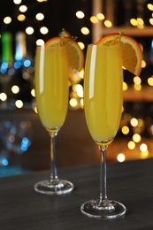 Photo of Mimosa cocktail with garnish on bar counter against blurred lights