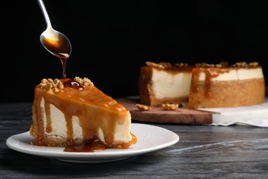 Photo of Pouring caramel sauce onto delicious piece of cheesecake with walnuts on black table, space for text