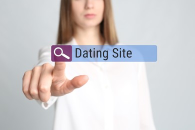 Image of Woman pointing at search bar with request Dating Site on light grey background, closeup