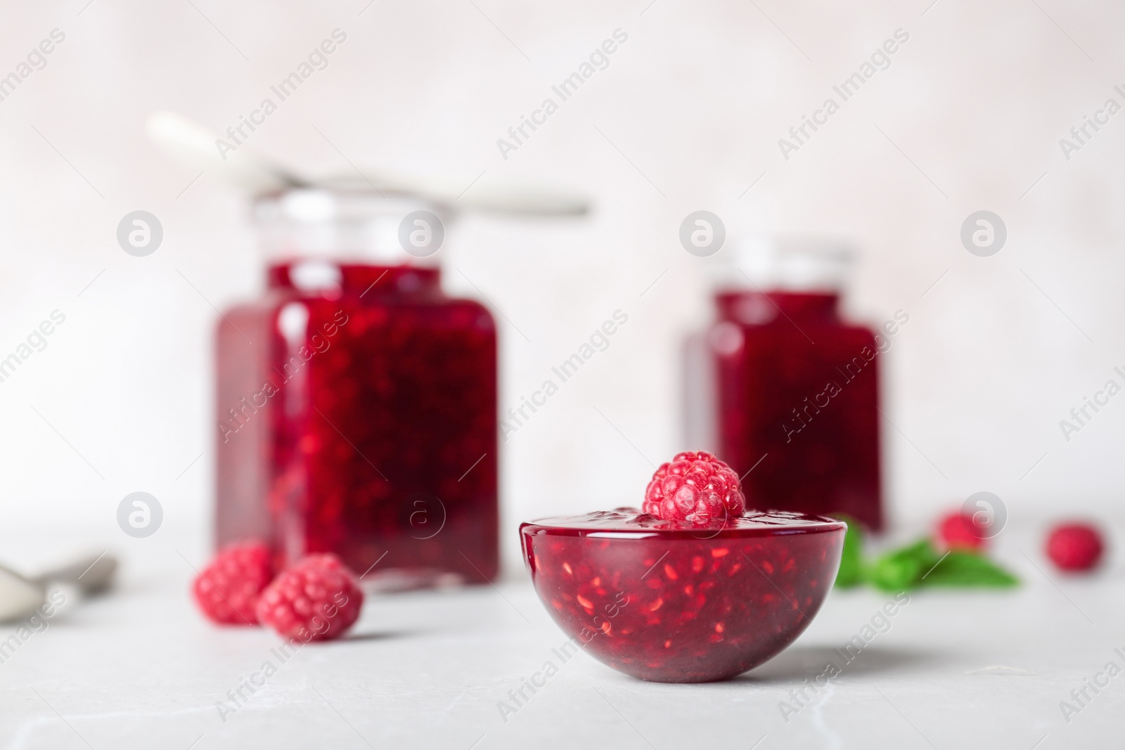 Photo of Bowl with delicious raspberry jam on table