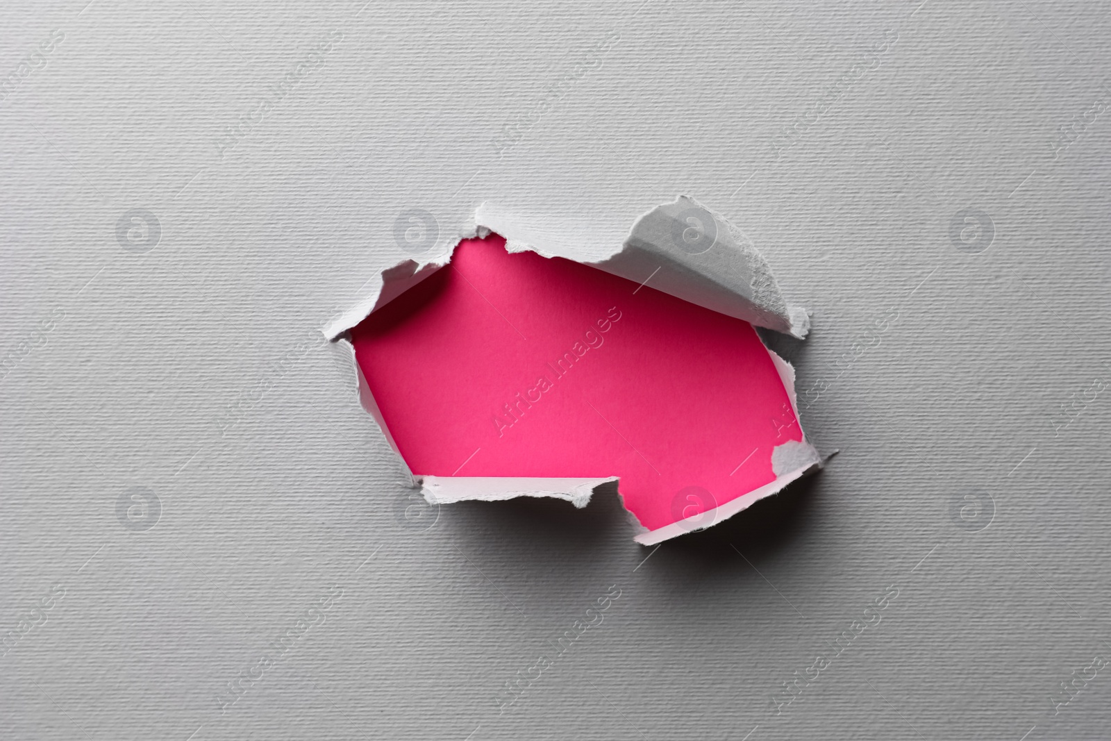 Photo of Hole in white paper on pink background