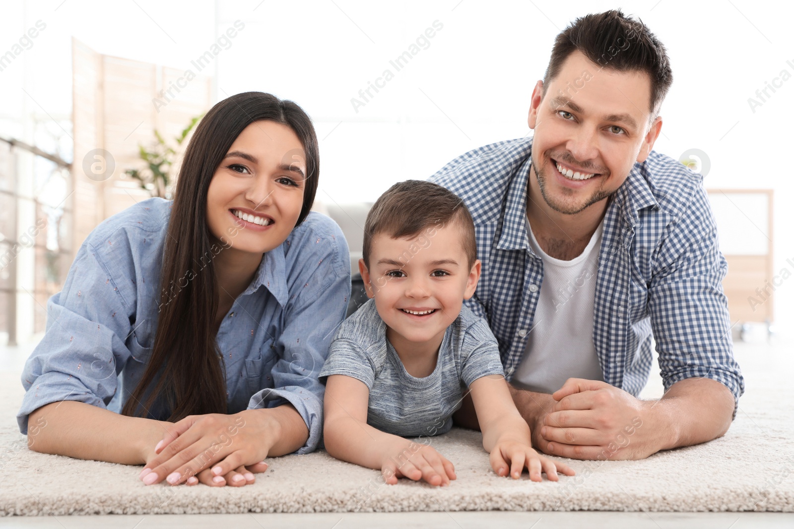 Photo of Happy couple and their son lying on carpet at home. Family time