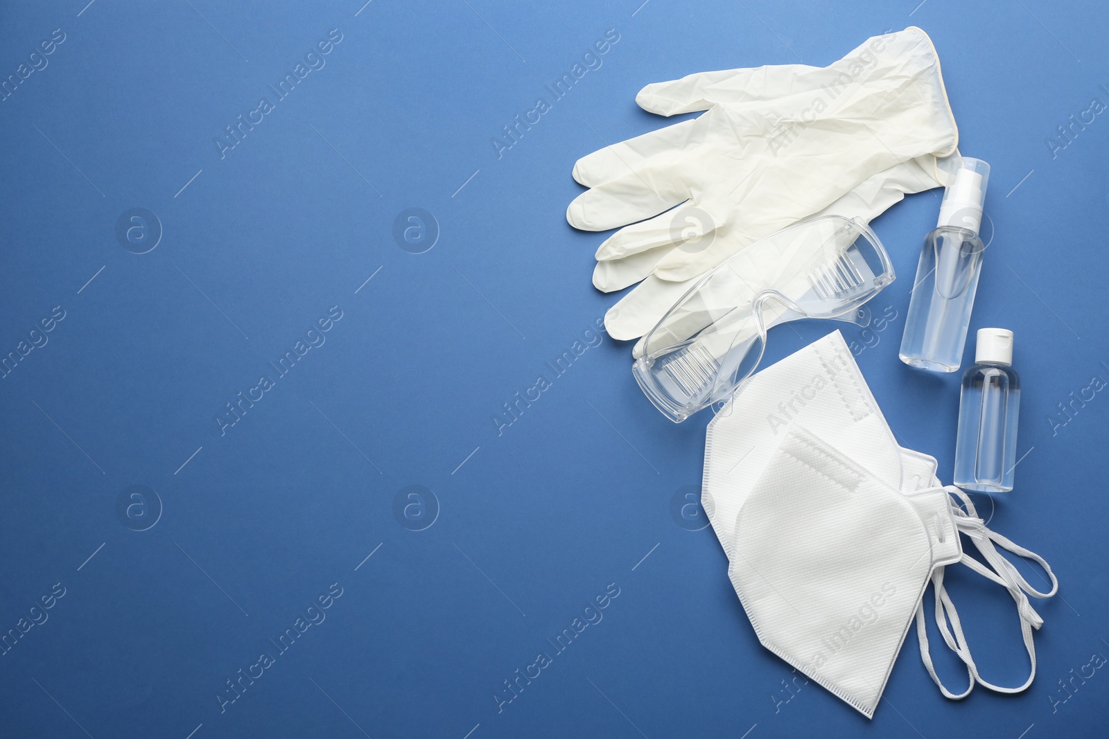 Photo of Flat lay composition with medical gloves, masks and hand sanitizer on blue background. Space for text