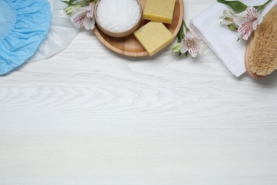 Photo of Flat lay composition with shower caps and toiletries on white wooden background. Space for text