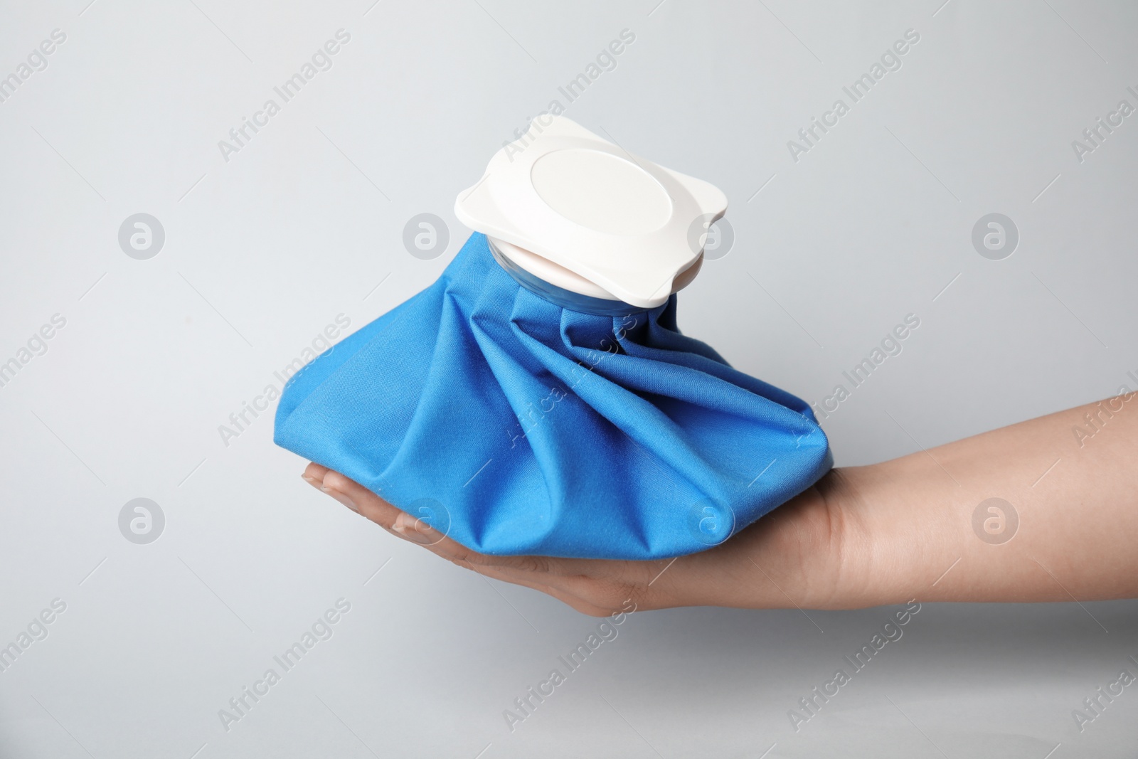 Photo of Woman holding ice pack against light background, closeup