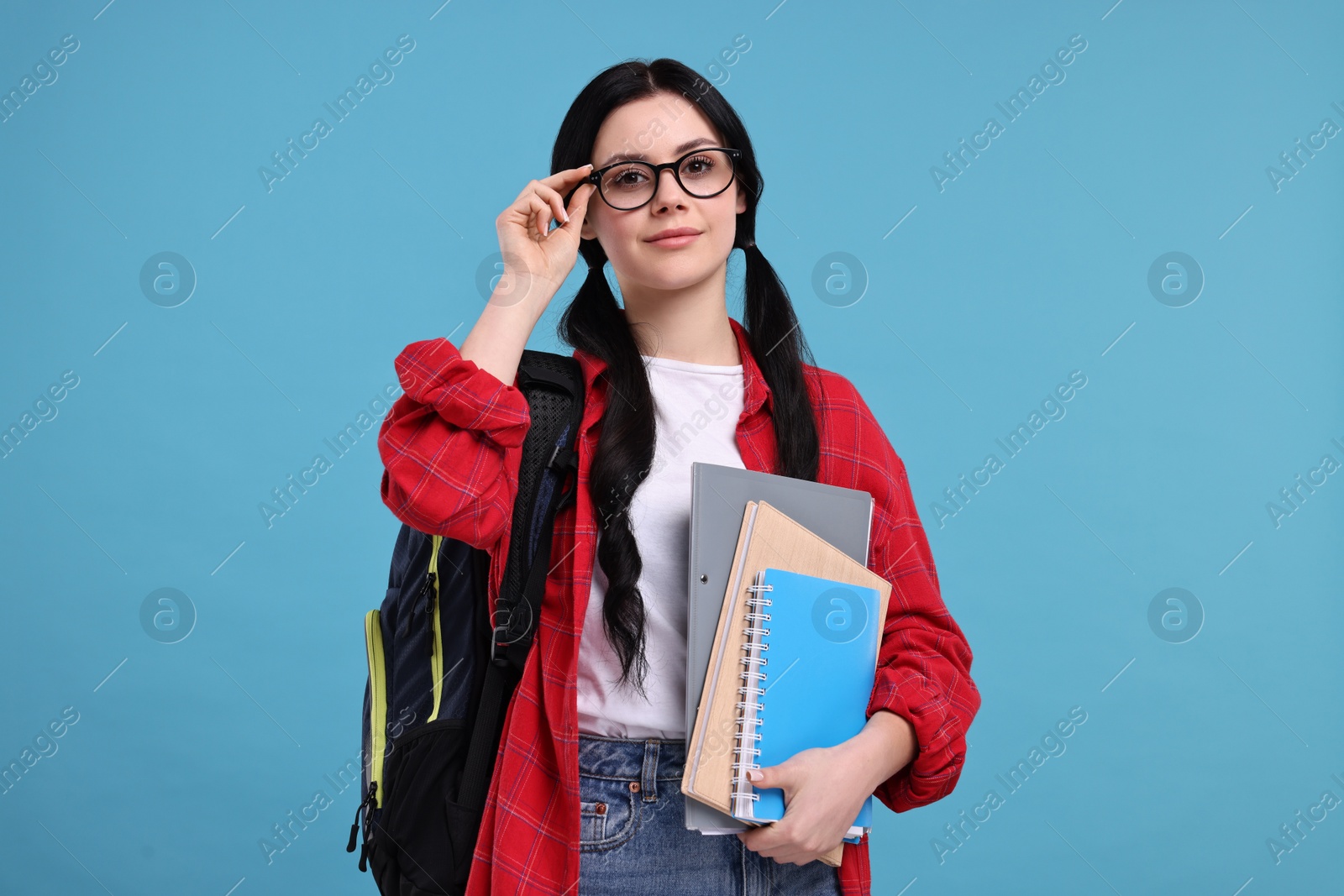 Photo of Student with notebooks, folder and backpack on light blue background