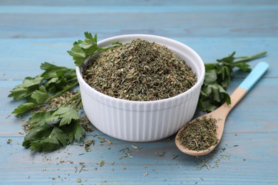Photo of Dried parsley and fresh leaves on light blue wooden table, closeup