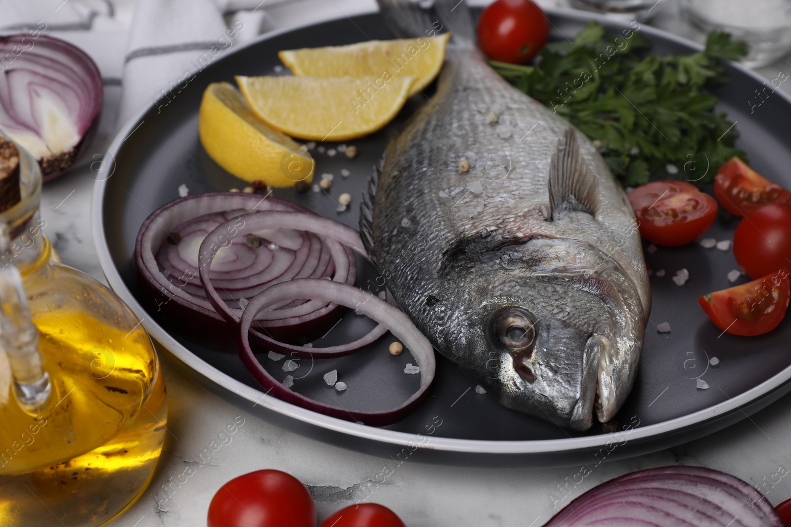 Photo of Fresh dorado fish and ingredients on white marble table, closeup