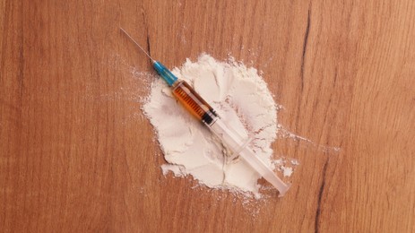Photo of Powder and syringe on wooden table, flat lay. Hard drugs