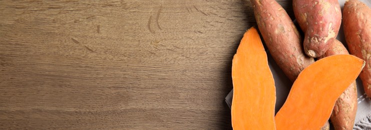 Sweet potatoes and space for text on wooden table, top view. Banner design